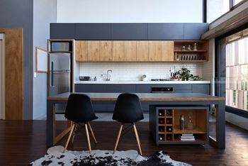 A kitchen with a table and chairs in front of a refrigerator at Coro Apartments, Los Angeles