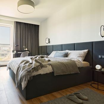 A bedroom with a large bed and a window with curtains at Coro Apartments, Los Angeles, California