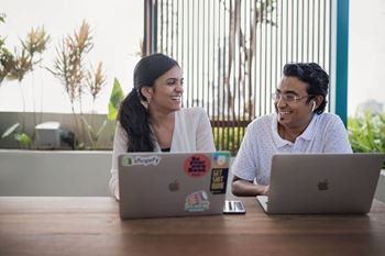 Two people sitting at a table with laptops at Coro Apartments, California 90016