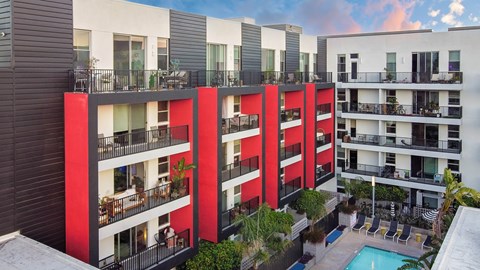 A modern apartment complex with red accents and a pool.