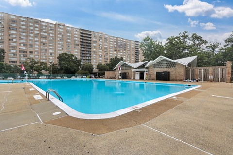 A large swimming pool in front of a tall apartment building.