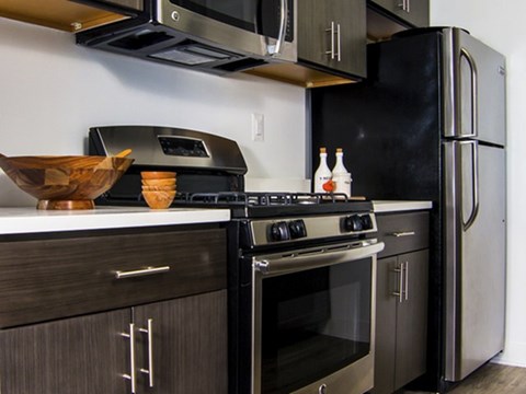 A black stove top oven with a black refrigerator in a kitchen.
