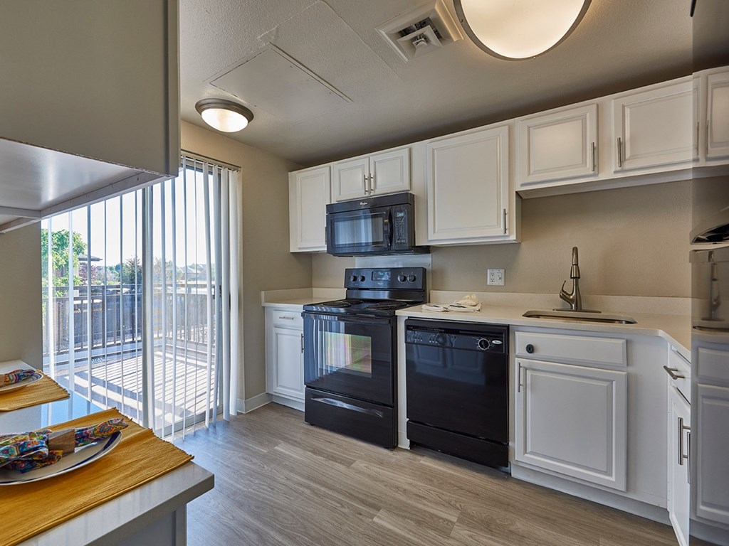 A modern kitchen with black appliances and white cabinets. at The Lex At Lowry, Denver