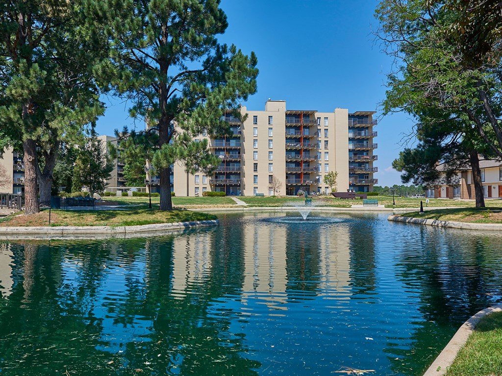A pond in front of a residential building surrounded by trees. at The Lex At Lowry, Denver, Colorado
