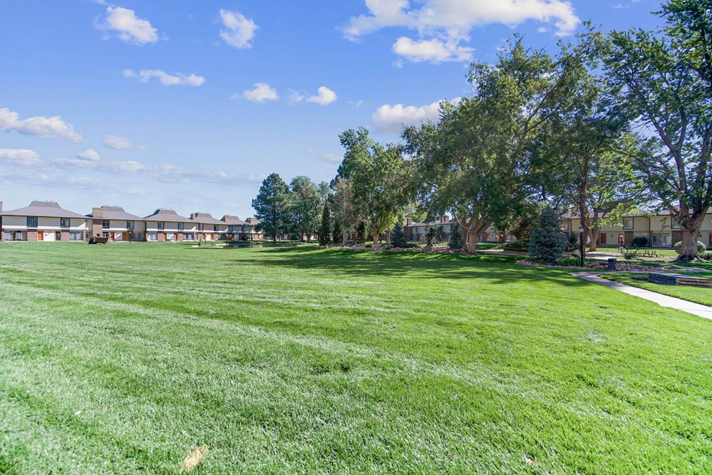 A grassy field with trees and houses in the background. at The Lex At Lowry, Denver, 80224