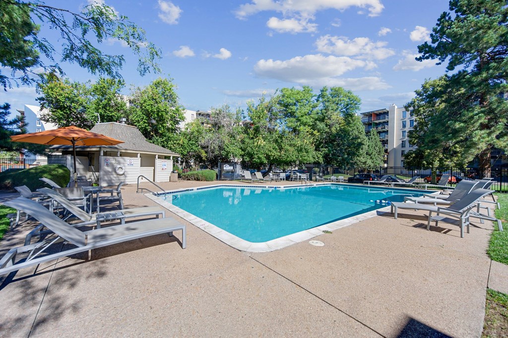 A swimming pool surrounded by trees and a building in the background. at The Lex At Lowry, Denver, Colorado