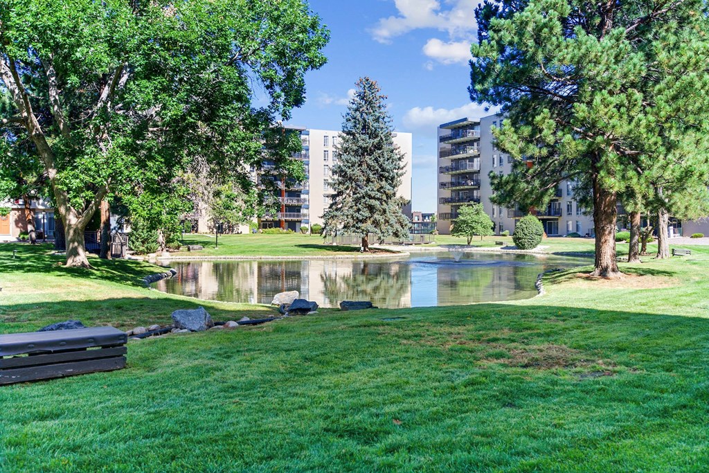 A park with a pond, trees and buildings in the background. at The Lex At Lowry, Denver, 80224