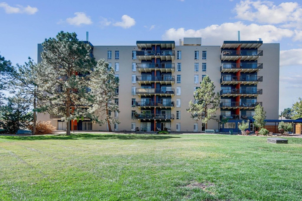 A large apartment building with balconies and a green lawn in front. at The Lex At Lowry, Denver, Colorado