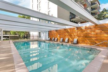 A large indoor swimming pool with a wooden wall and lounge chairs. at The Lex At Lowry, Denver, Colorado