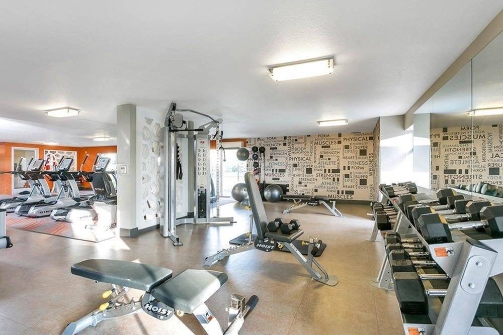 A gym with a variety of equipment including treadmills, weights, and exercise machines. at The Lex At Lowry, Denver