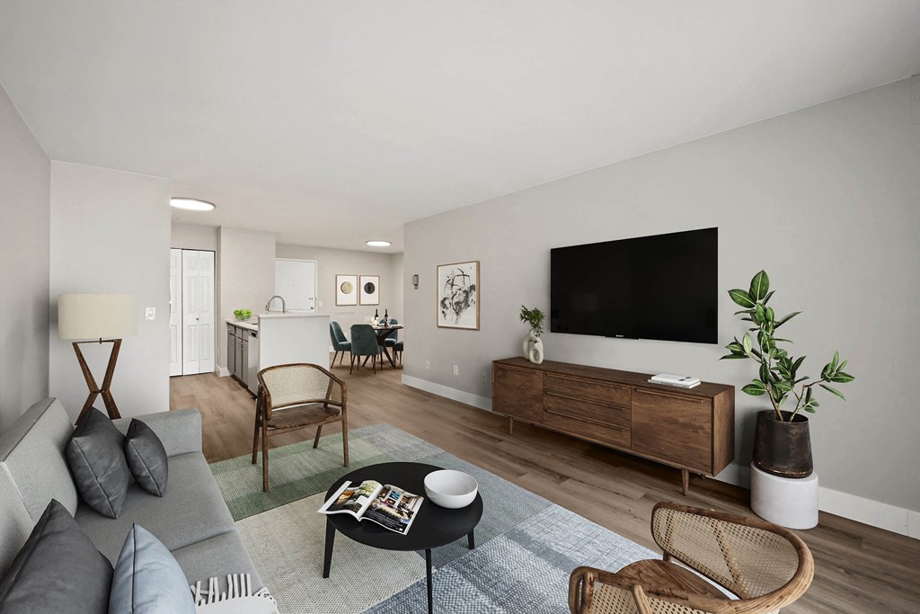 A living room with a grey couch, a black coffee table, and a flat screen TV on a wooden cabinet. at The Lex At Lowry, Denver