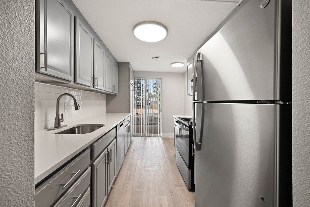 A modern kitchen with stainless steel appliances and wooden floors. at The Lex At Lowry, Denver, CO
