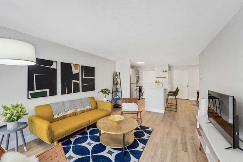 A living room with a yellow couch and a blue and white rug. at The Lex At Lowry, Denver, CO