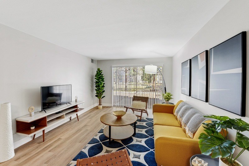 A living room with a television, a yellow couch, and a blue and white rug. at The Lex At Lowry, Denver, CO, 80224