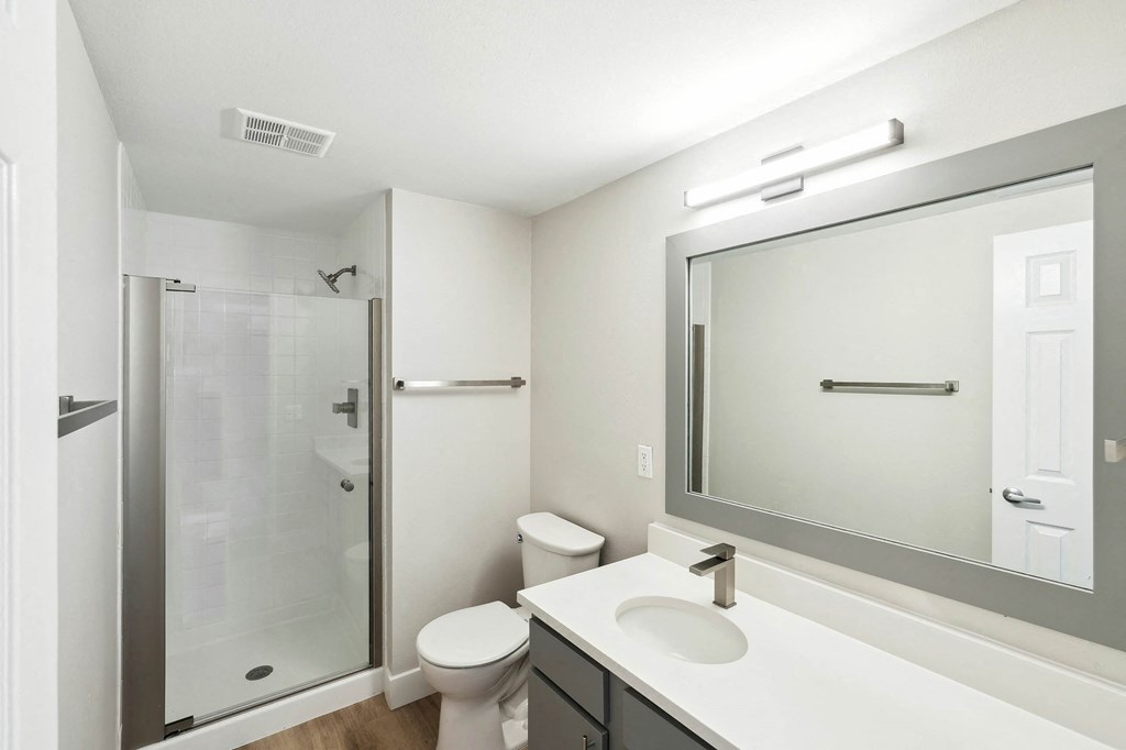 A white bathroom with a toilet, sink, and shower. at The Lex At Lowry, Denver, 80224