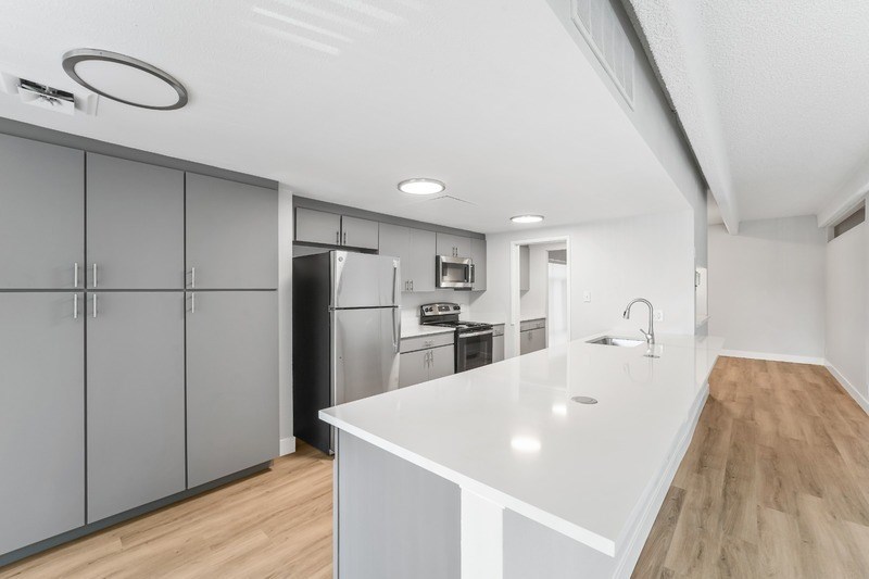 A modern kitchen with a white countertop and wooden flooring. at The Lex At Lowry, Denver, Colorado