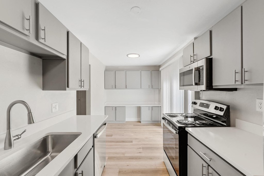 A modern kitchen with stainless steel appliances and white cabinets. at The Lex At Lowry, Denver