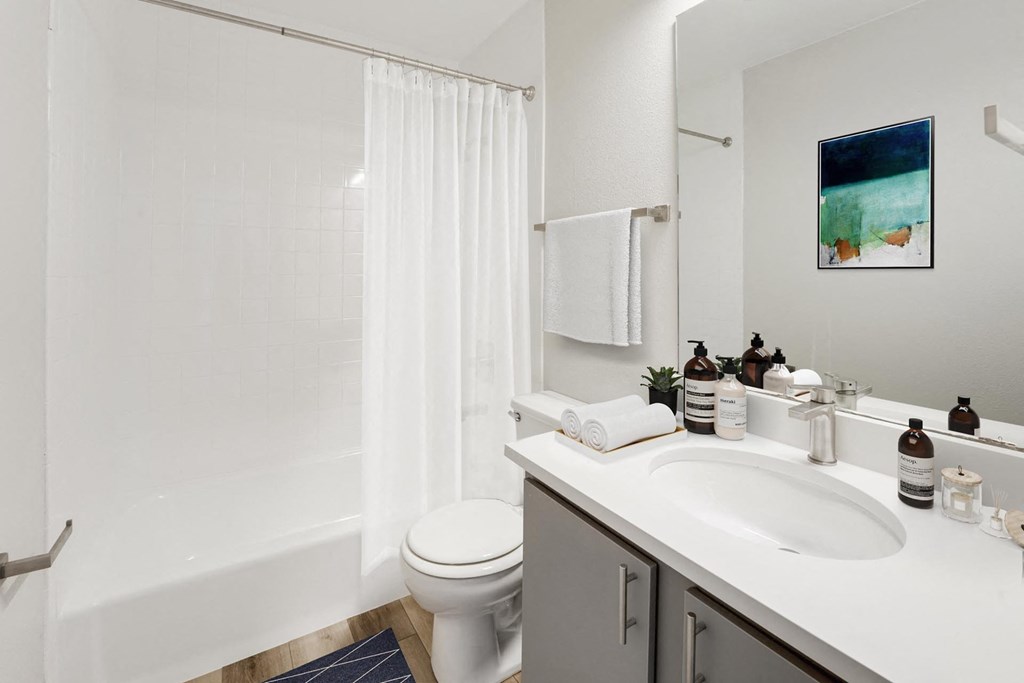 A white bathroom with a toilet, sink, and shower. at The Lex At Lowry, Denver
