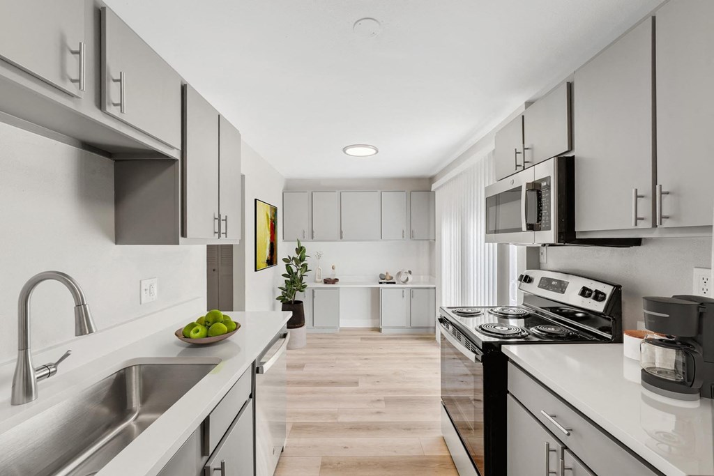 A modern kitchen with stainless steel appliances and white cabinets. at The Lex At Lowry, Denver