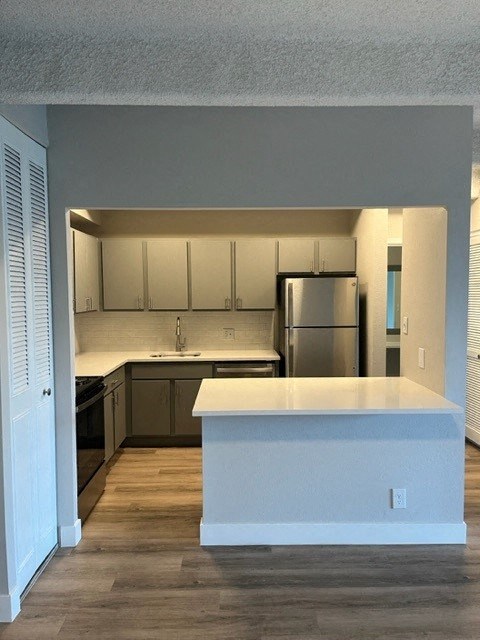 A kitchen with a white countertop and wooden floors. at The Lex At Lowry, Denver