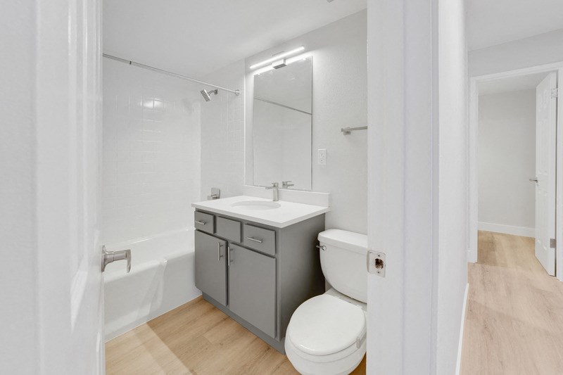 A white toilet sits next to a sink in a small bathroom. at The Lex At Lowry, Colorado