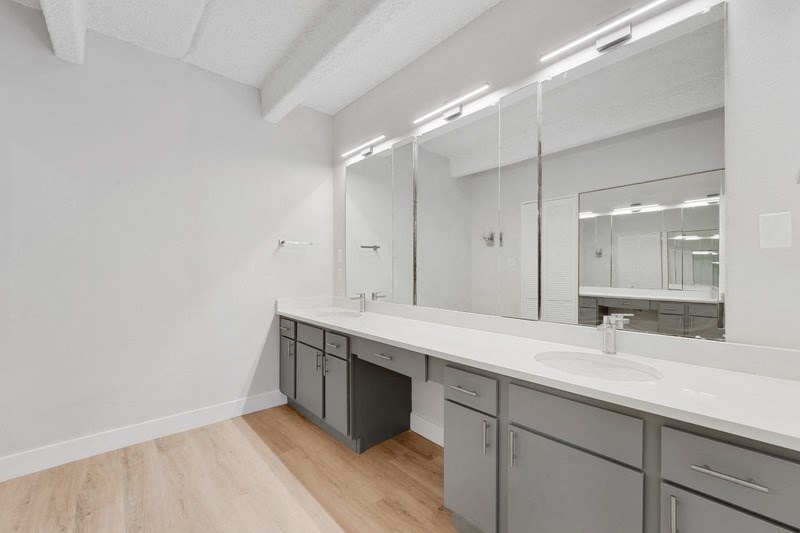 A bathroom with a sink, mirror, and cabinets. at The Lex At Lowry, Denver