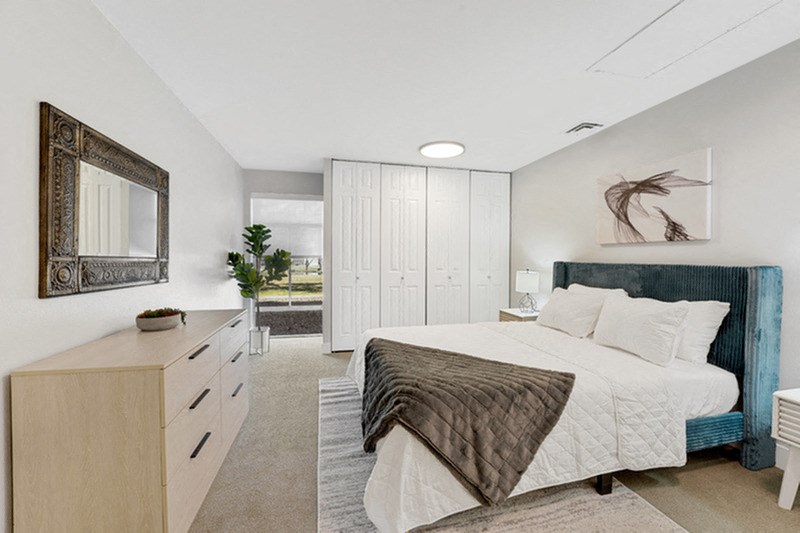 A bedroom with a large bed and a mirror on the wall. at The Lex At Lowry, Denver, 80224