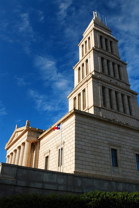 A tall building with a tower and a flag on top.