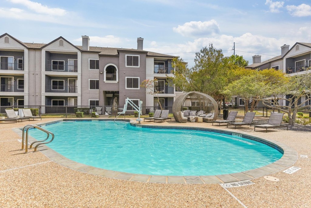 A large swimming pool is surrounded by a concrete patio and chairs. A large swimming pool is surrounded by a concrete patio and chairs.at Onyx183, Austin Texas
