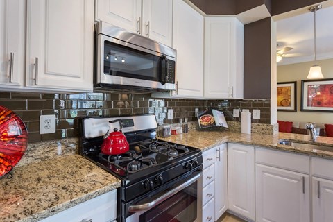 A kitchen with a black stove top and white cabinets.