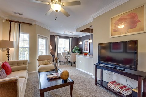 A living room with a television, a couch, a chair, a coffee table, and a painting on the wall.