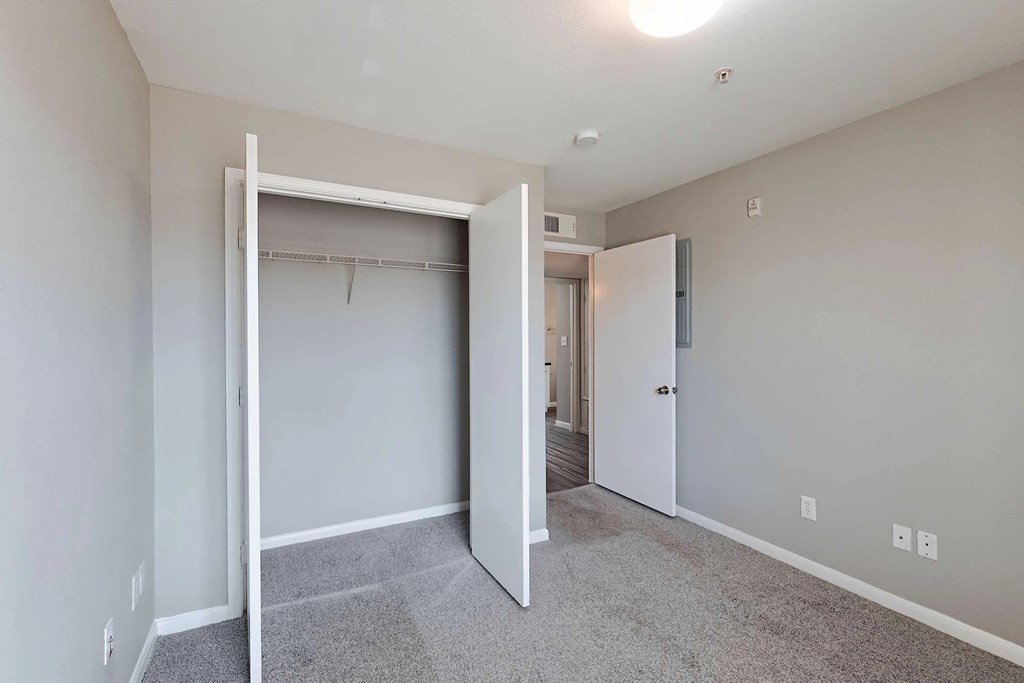 A room with a white door and a grey carpet.