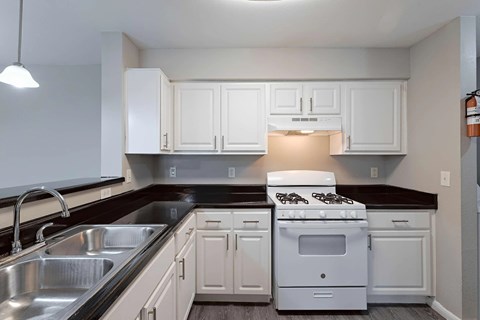 A white stove and oven in a kitchen with white cabinets.