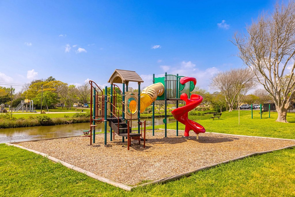 A playground with a red slide and a yellow slide.