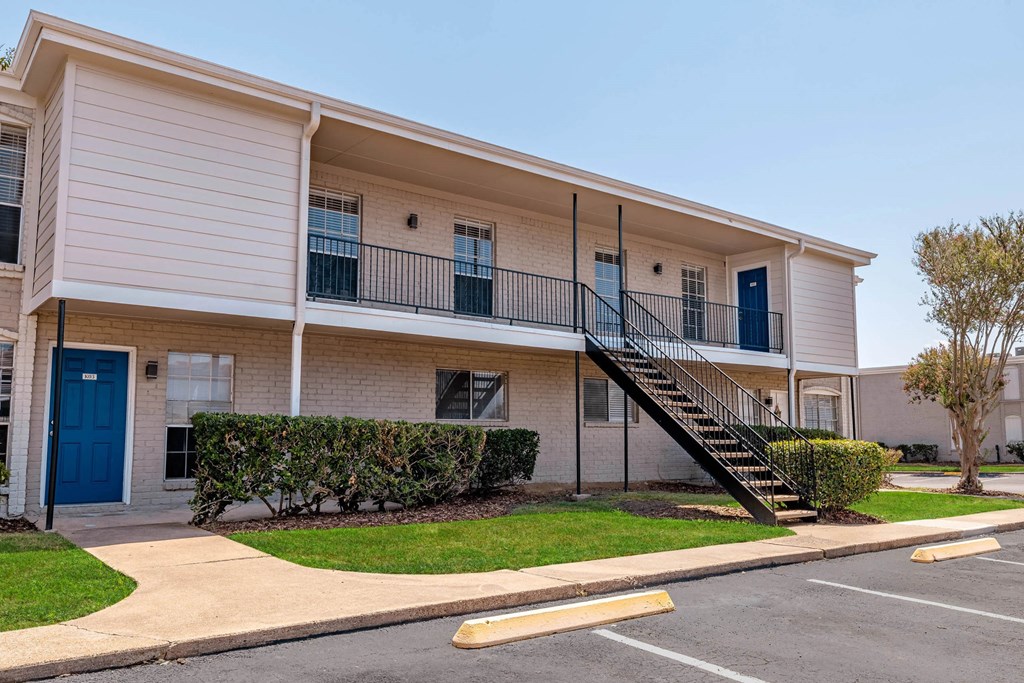 A building with a blue door and a staircase leading to the second floor.