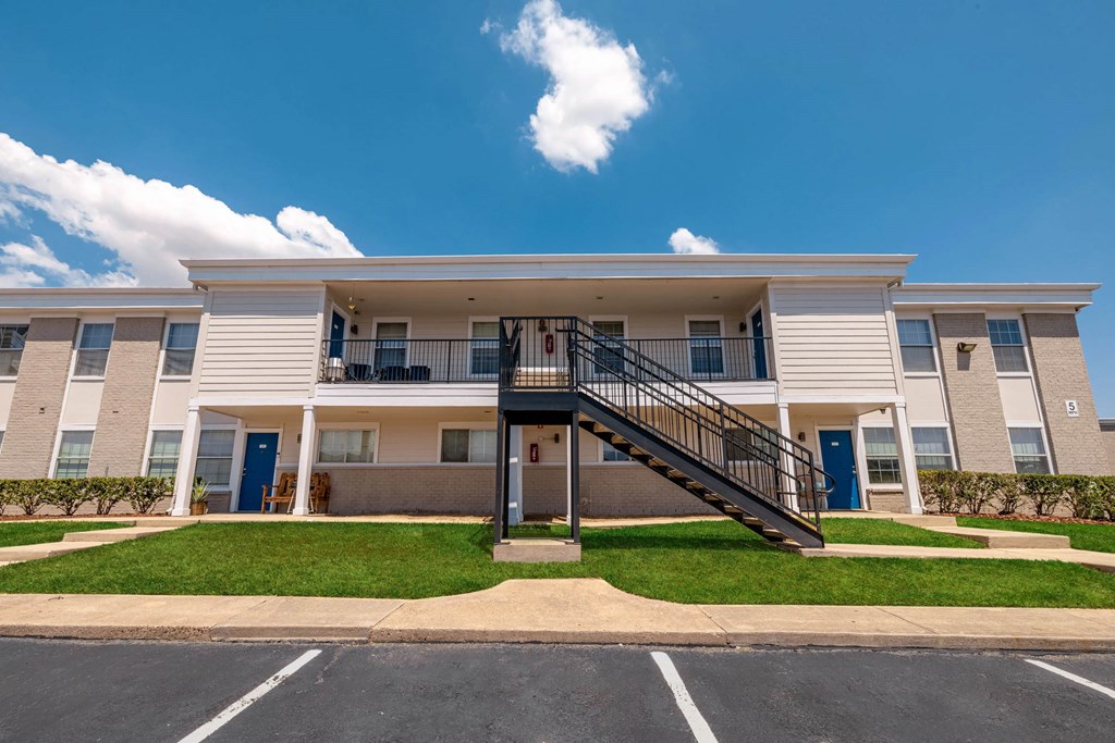 A large white apartment building with a black staircase leading to the entrance.