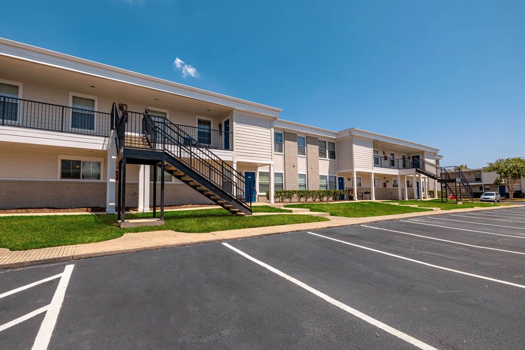 A parking lot in front of a building with a clear blue sky.