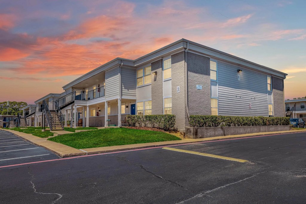 A modern apartment building with a parking lot in front.