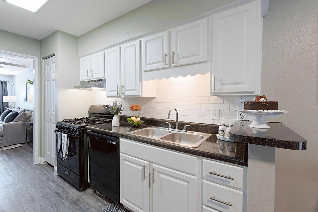 A kitchen with black appliances and white cabinets.