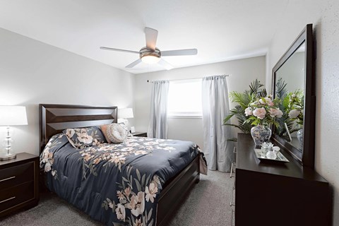 A bedroom with a bed, nightstand, and a painting on the wall.