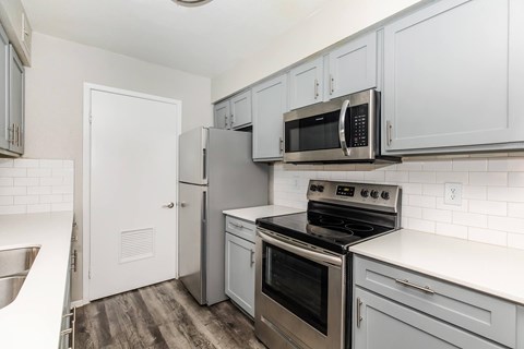 A kitchen with a stove top oven, microwave, and refrigerator.