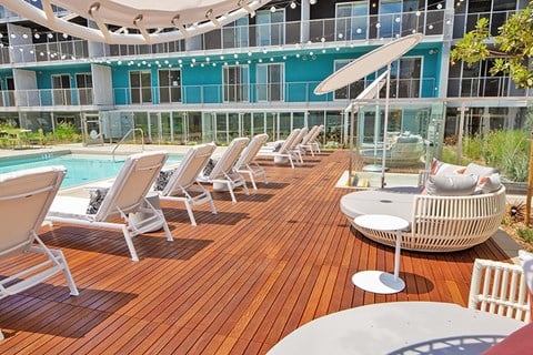 A poolside deck with sun loungers and a table. A poolside deck with sun loungers and a table.at Prizma, Los Angeles, CA