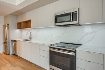 A modern kitchen with a stainless steel refrigerator, microwave, and oven.at Prizma, Los Angeles  