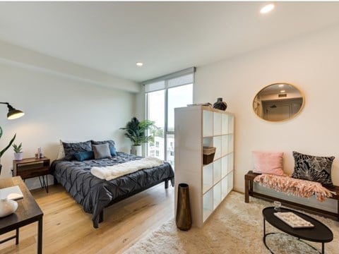 A bedroom with a bed, a bench, and a mirror on the wall. A bedroom with a bed, a bench, and a mirror on the wall.at Prizma, California, 90038
