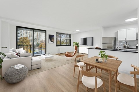 A modern living room with a white sofa, a wooden dining table, and a kitchen in the background.