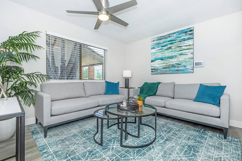 A living room with a grey couch, a coffee table, and a ceiling fan.at Solara, Phoenix