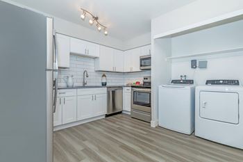 A modern kitchen with white appliances and wooden flooring.at Solara, Arizona, 85033