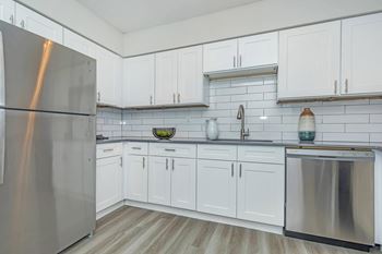 A kitchen with white cabinets and a stainless steel refrigerator.at Solara, Phoenix