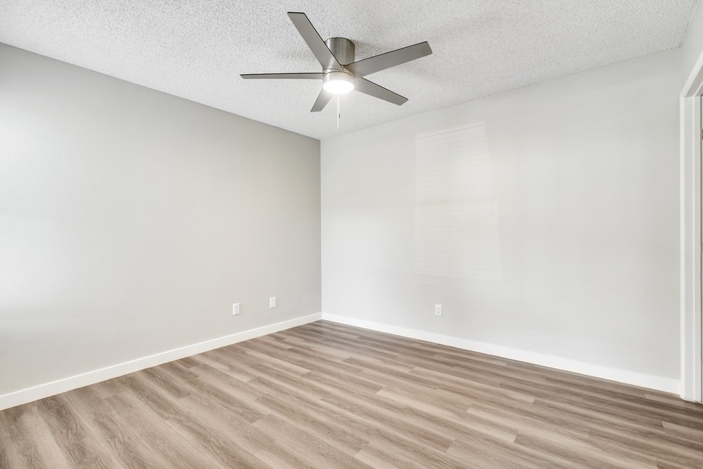 A room with a ceiling fan and wooden flooring.at Solara, Arizona