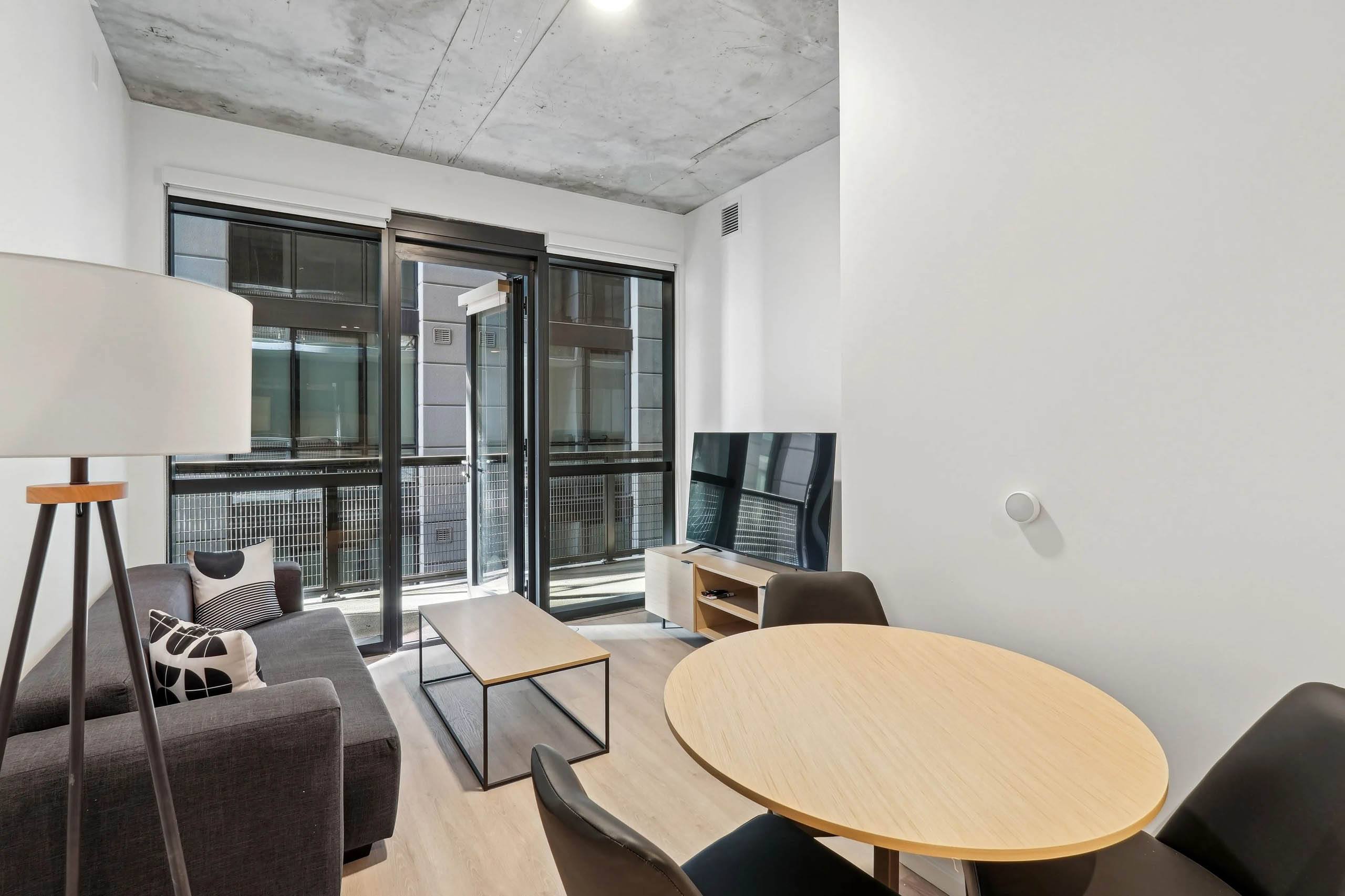 A modern living room with a wooden table and black couch.